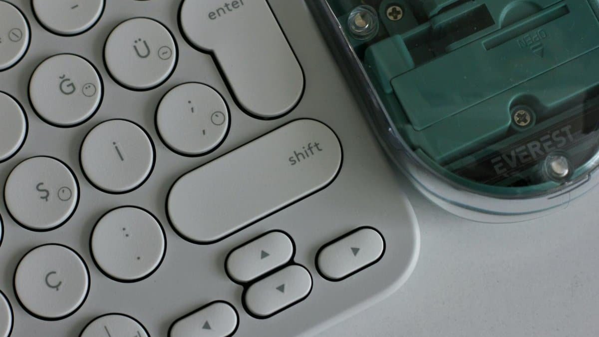 Close-up photo of a wireless keyboard with circular keys and a transparent-bodied mouse, showcasing modern computer accessories.