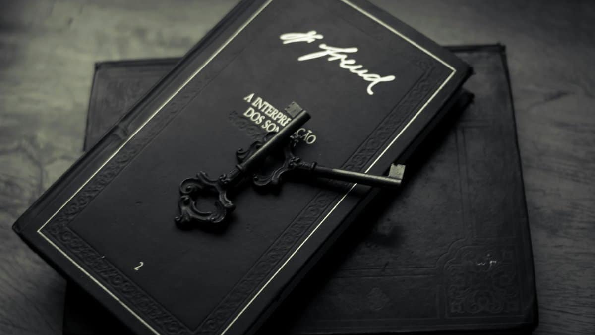 From above of classic metal key placed on black books on wooden table
