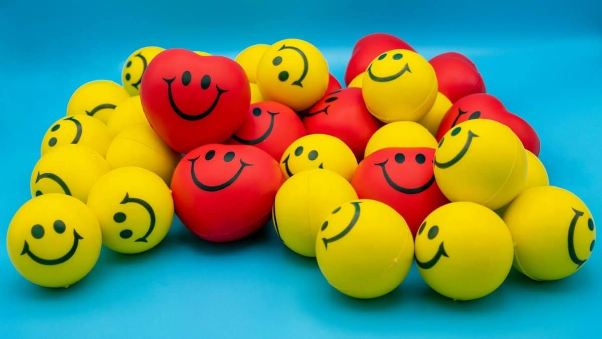 A collection of vibrant yellow and red smiley stress balls arranged on a blue surface.