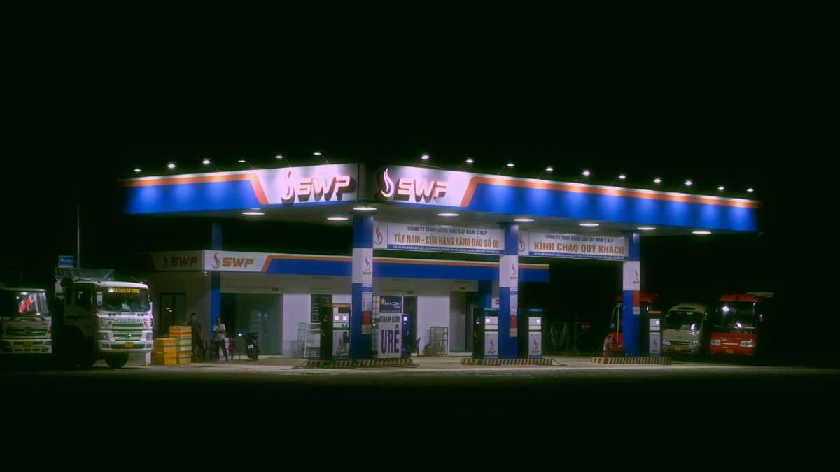 Nighttime view of a brightly lit gas station with trucks and cars parked.