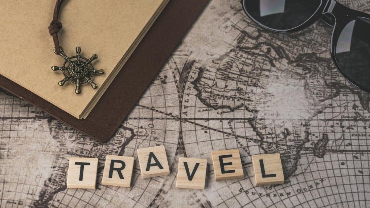 Close-up of travel items including map, helm pendant, notebook, and sunglasses.