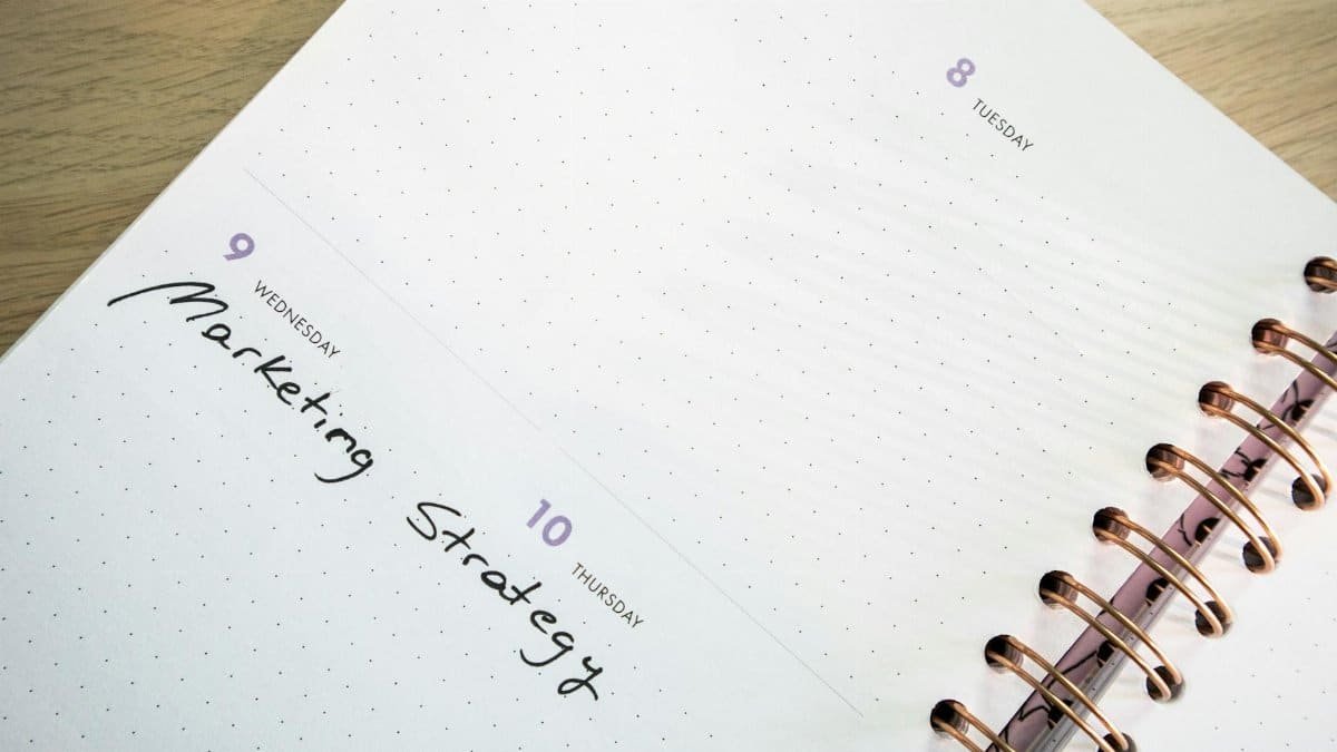 Detailed spiral-bound planner showing marketing strategy notes. Perfect for time management themes.