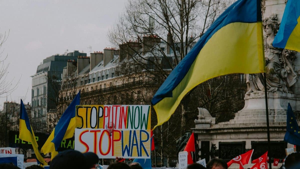 A dynamic crowd in Paris rallies with Ukrainian flags and anti-war signs, advocating peace.