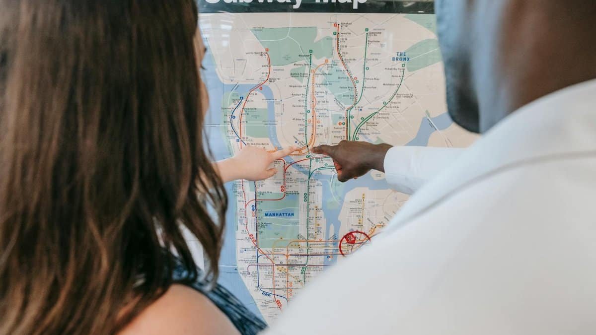 A couple examines a subway map, planning their route at a station.