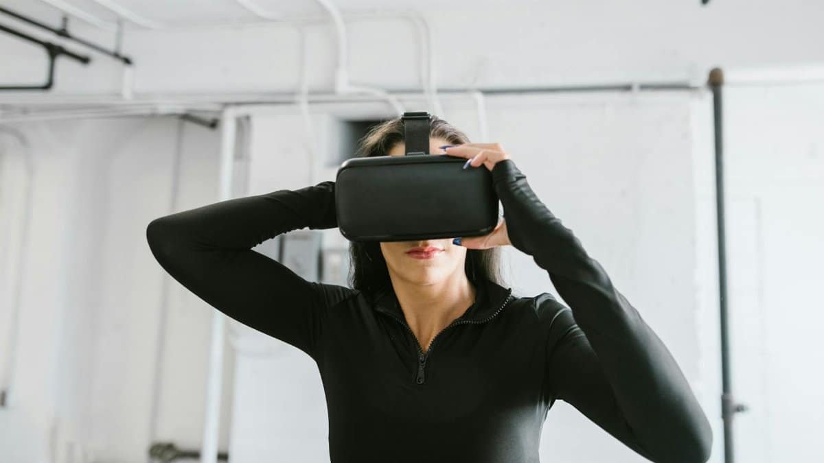 Woman wearing black long sleeve using virtual reality headset indoors, exploring immersive technology.