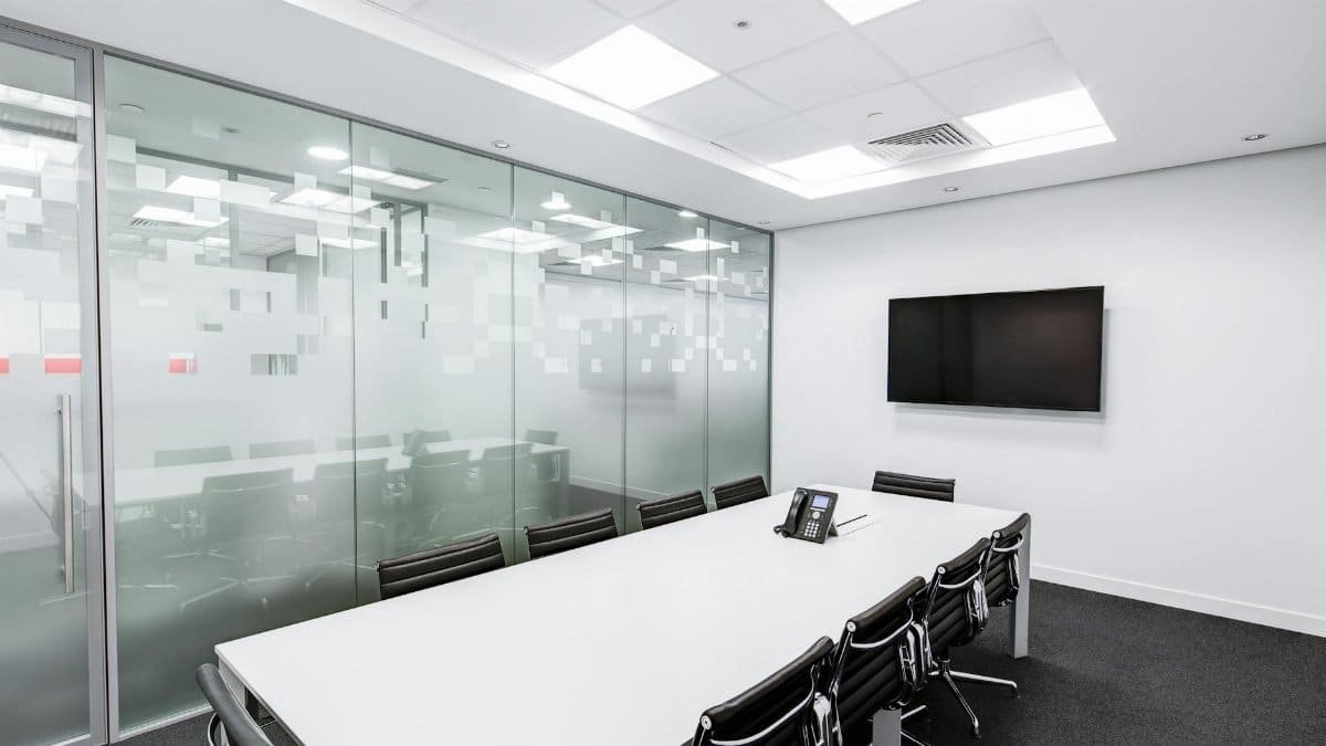Sleek, minimalist conference room with glass walls, long table, and office chairs.