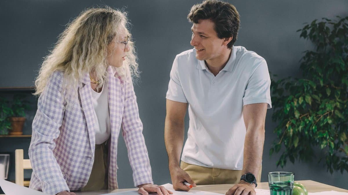 Two colleagues discussing project plans in a modern office environment with a collaborative atmosphere.