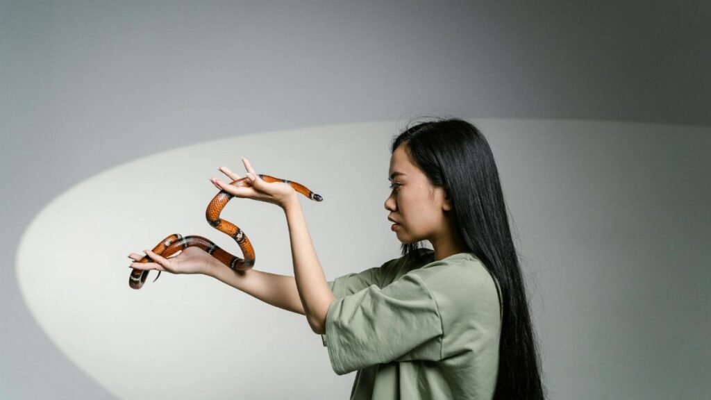 A woman confronting her fear by holding a snake, symbolizing overcoming anxiety.