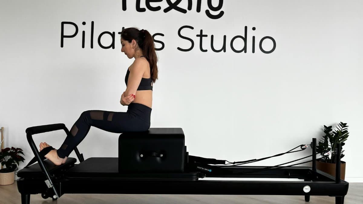 Focused woman practicing on a Pilates reformer in a modern studio.
