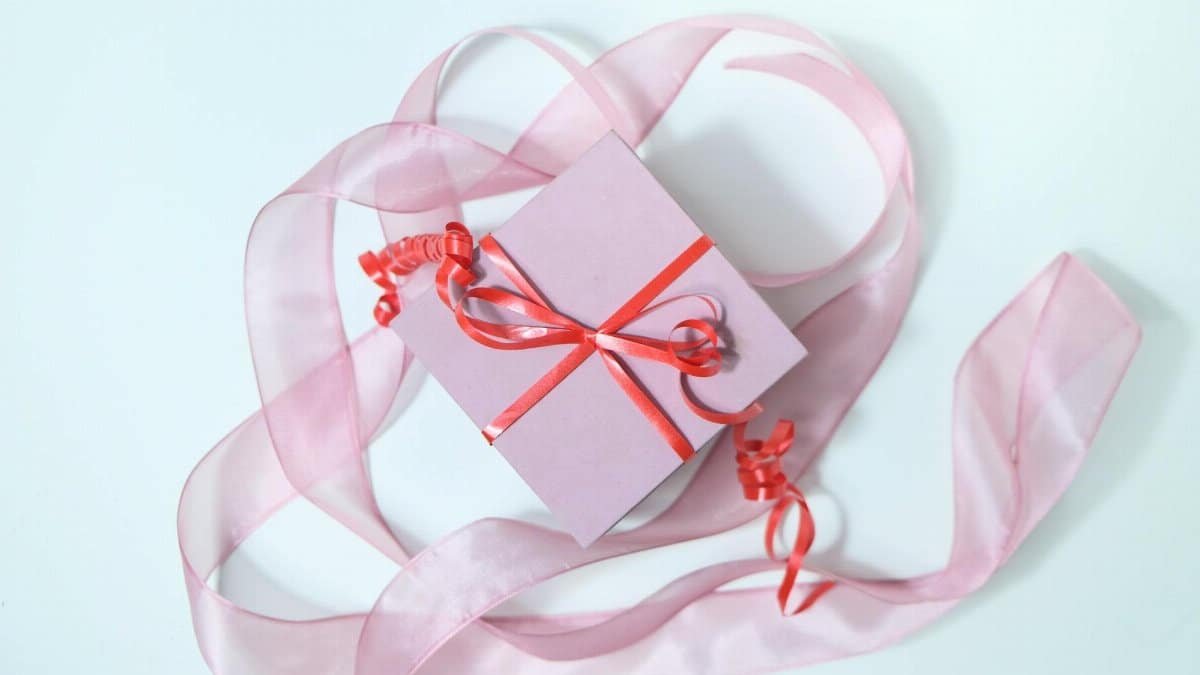 Stylish pink gift box with vibrant red ribbon, perfect for celebrations.