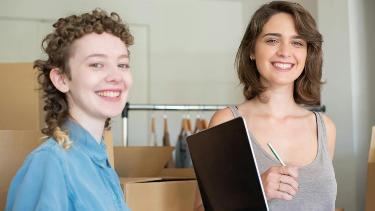 Two smiling women working together in a home-based business with boxes and a laptop.