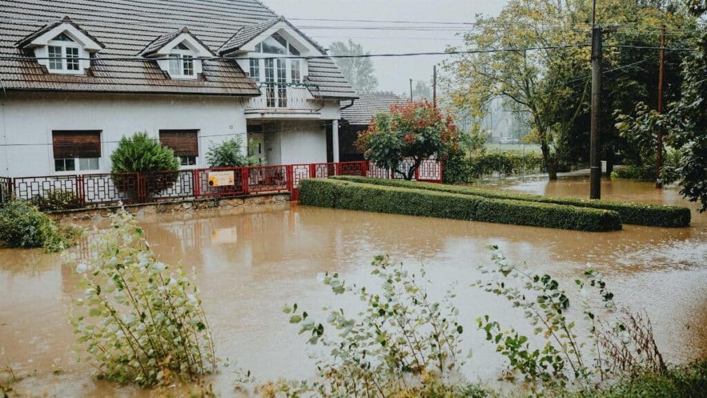 A suburban house surrounded by floodwaters after heavy rain, showing impact of natural disaster.