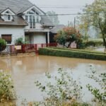 A suburban house surrounded by floodwaters after heavy rain, showing impact of natural disaster.