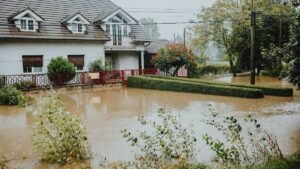 A suburban house surrounded by floodwaters after heavy rain, showing impact of natural disaster.