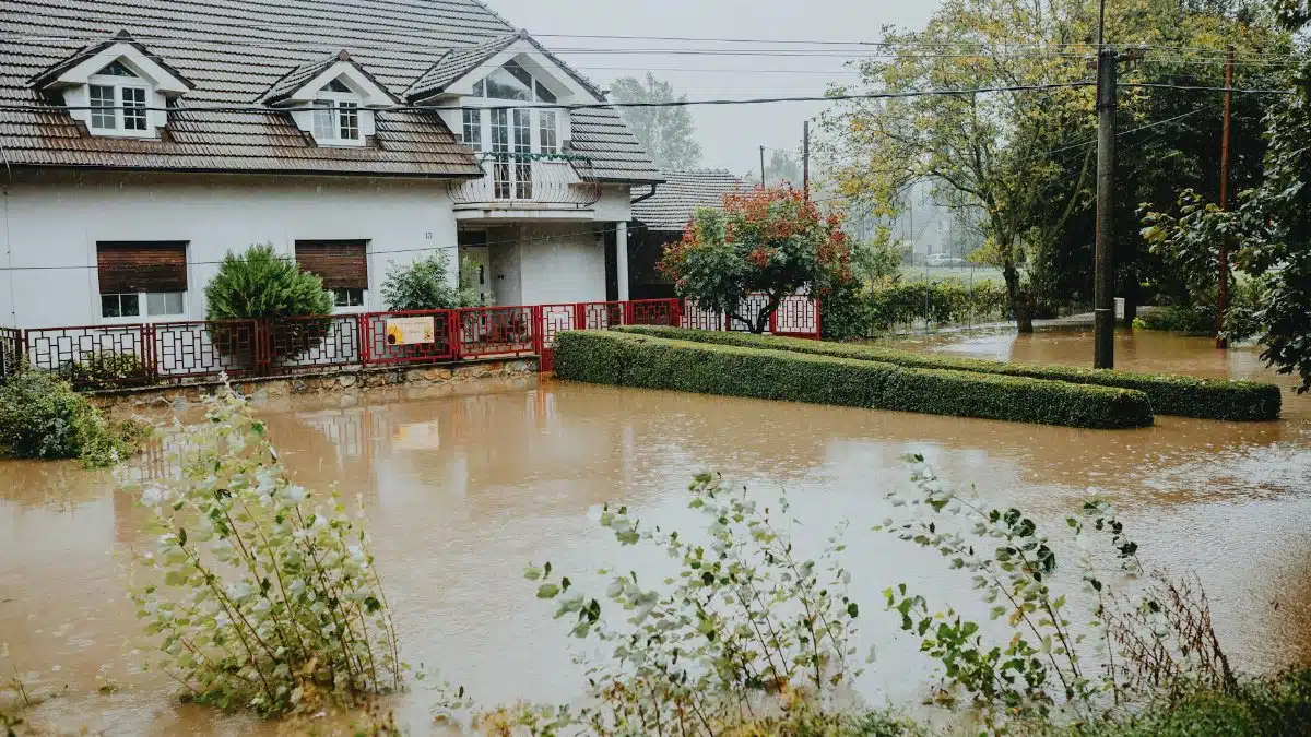 A suburban house surrounded by floodwaters after heavy rain, showing impact of natural disaster.