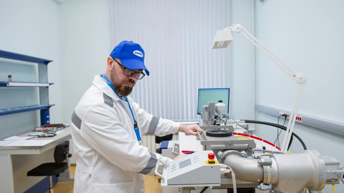 Lab technician in white coat operating advanced scientific equipment indoors