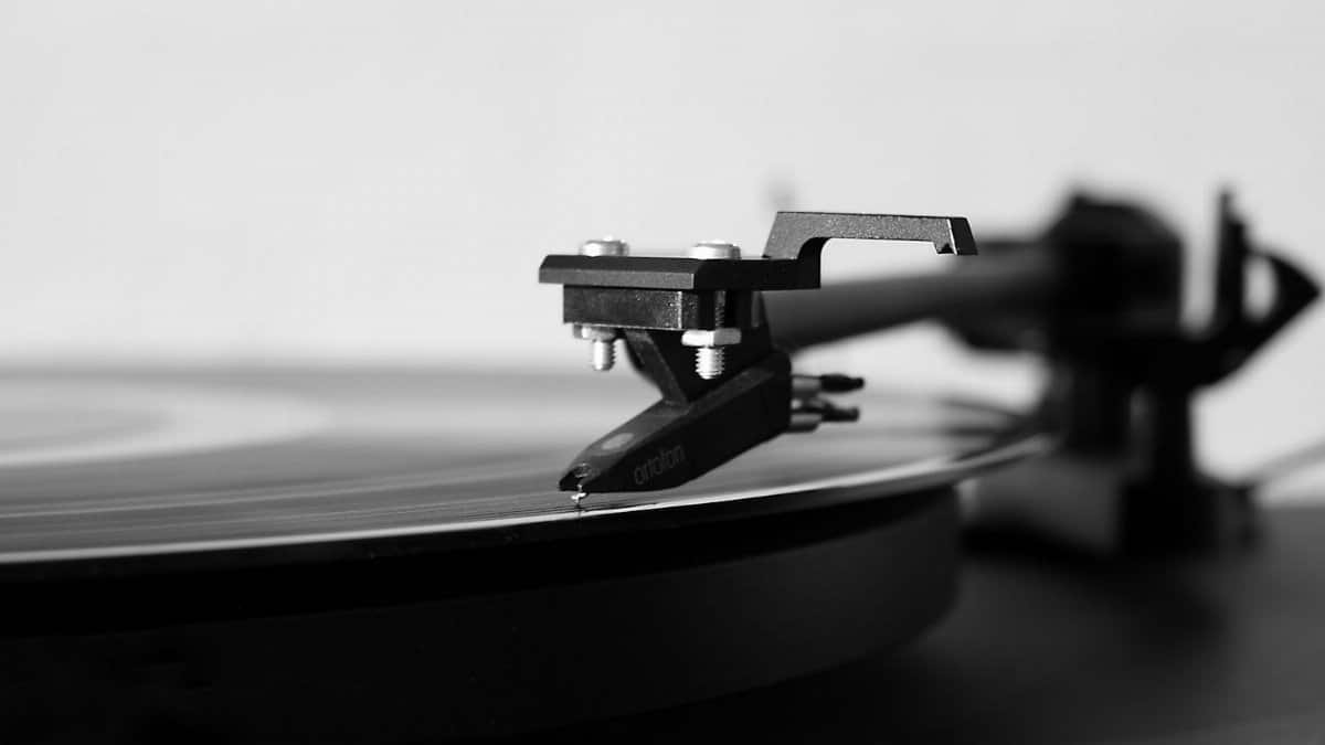 Black and white photo of a record player needle on a spinning vinyl, highlighting classic music technology.