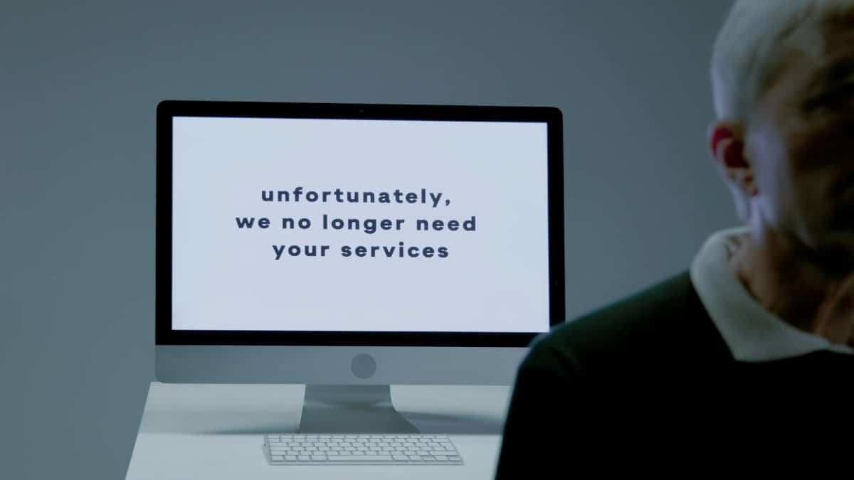 A computer screen displays a termination message, indicating job loss or unemployment.