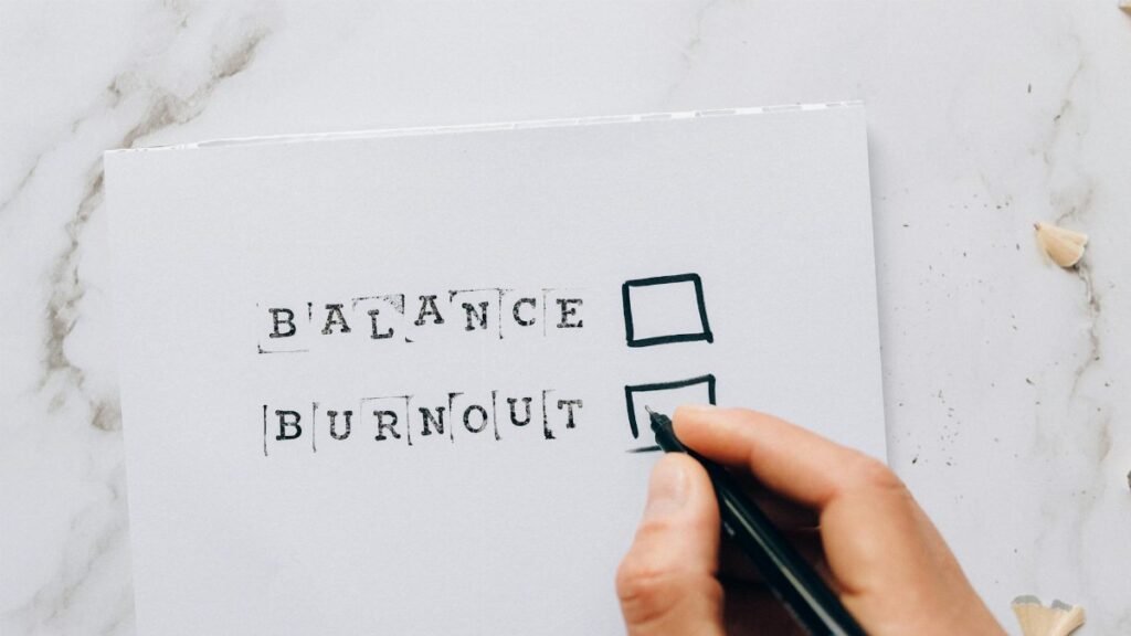 Close-up of a hand hovering over a checklist with options for balance or burnout, symbolizing stress and choice.