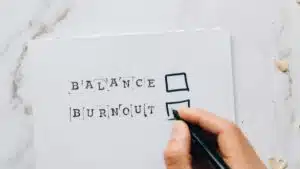 Close-up of a hand hovering over a checklist with options for balance or burnout, symbolizing stress and choice.
