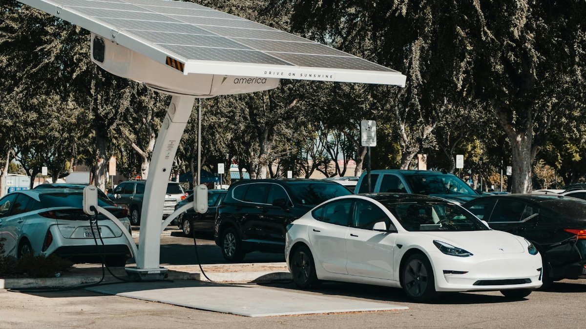 Electric car parked at a solar charging station outdoors, highlighting renewable energy and innovation.
