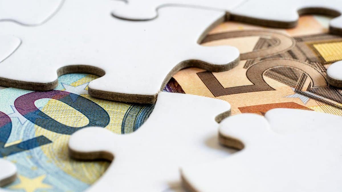 Close-up of euro banknotes revealed under puzzle pieces, symbolizing financial solutions.