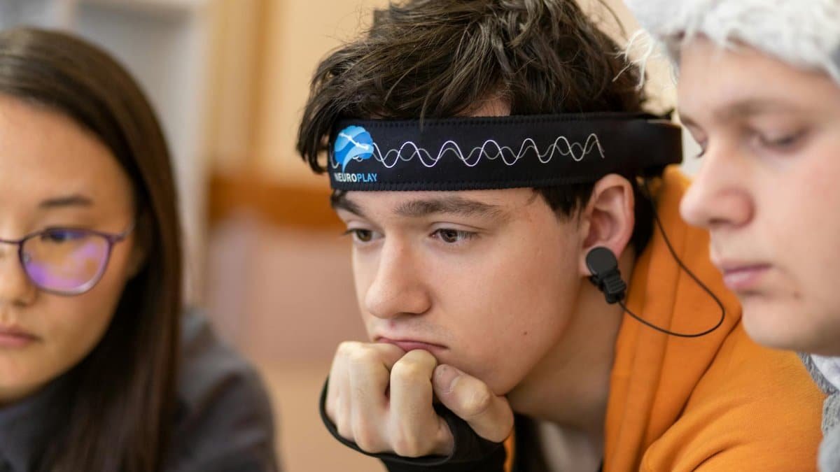 Teenagers engaged in a study session using a neurotech headband for focus and concentration.