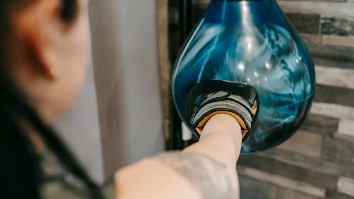 A focused woman punches a speed bag in a gym setting, showcasing strength and determination.