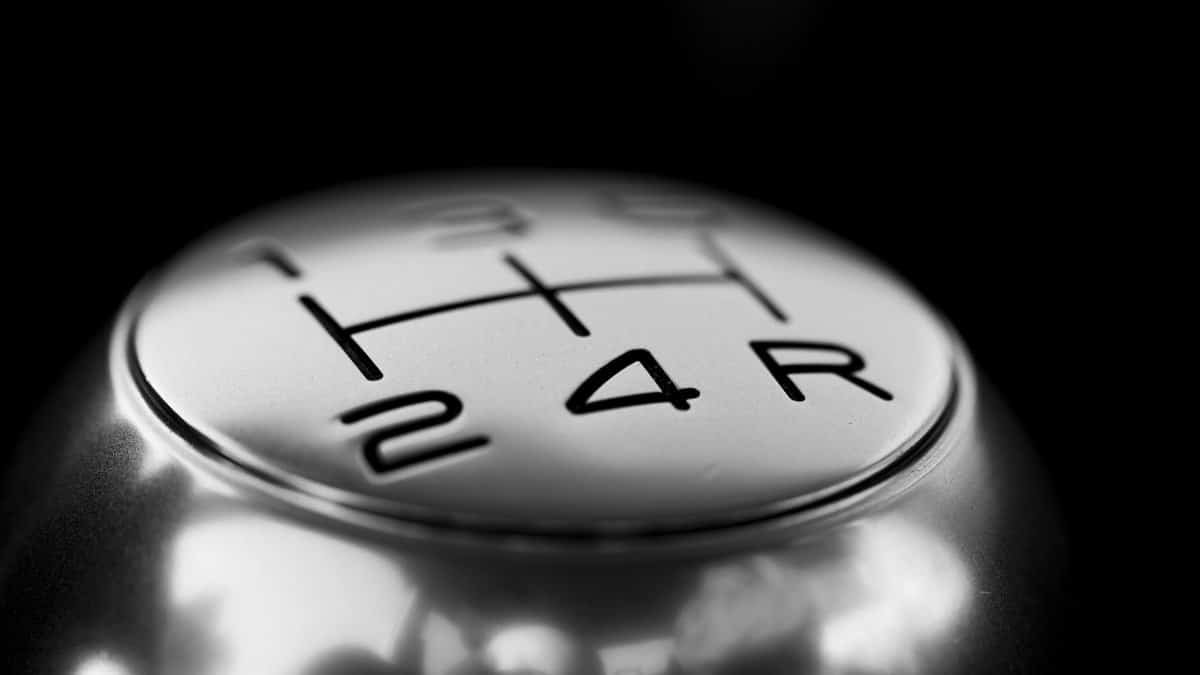High contrast black and white photo of a metallic gear shift knob, showcasing its chrome texture and engraved numbers.