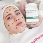 Woman receiving a skincare treatment holds Esthemax product. Spa and beauty setting.