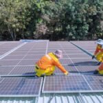 Team of workers installing solar panels on a sunny day, promoting renewable energy and sustainability.
