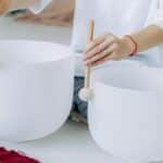 Close-up of hands playing crystal singing bowls for sound healing and meditation.
