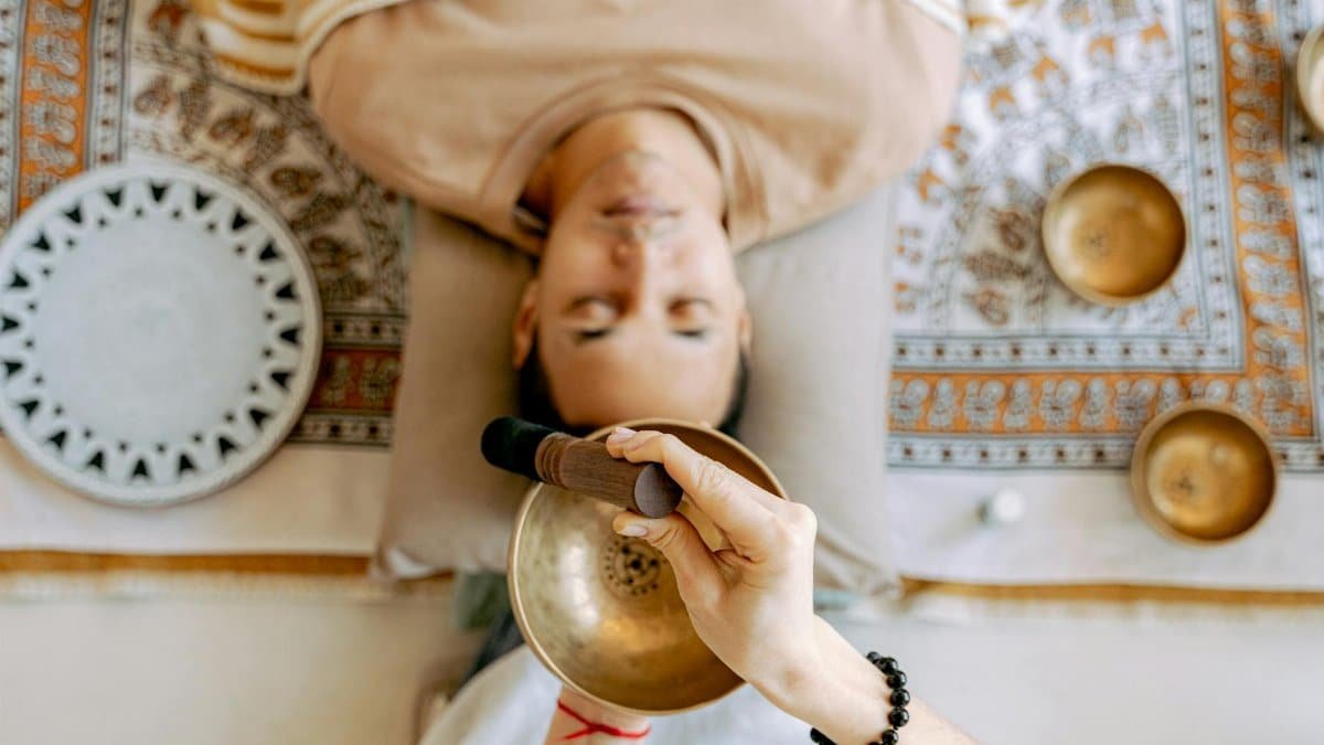 A man experiencing deep relaxation during a sound therapy session with Tibetan singing bowls for holistic wellness.