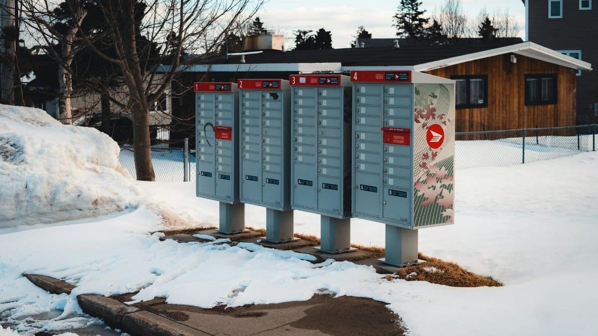 Community mailboxes in a snow-covered suburban neighborhood during winter season.