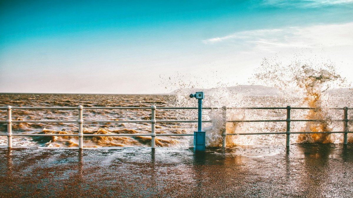 Vibrant ocean scene with waves crashing against a pier, creating a dramatic splash.