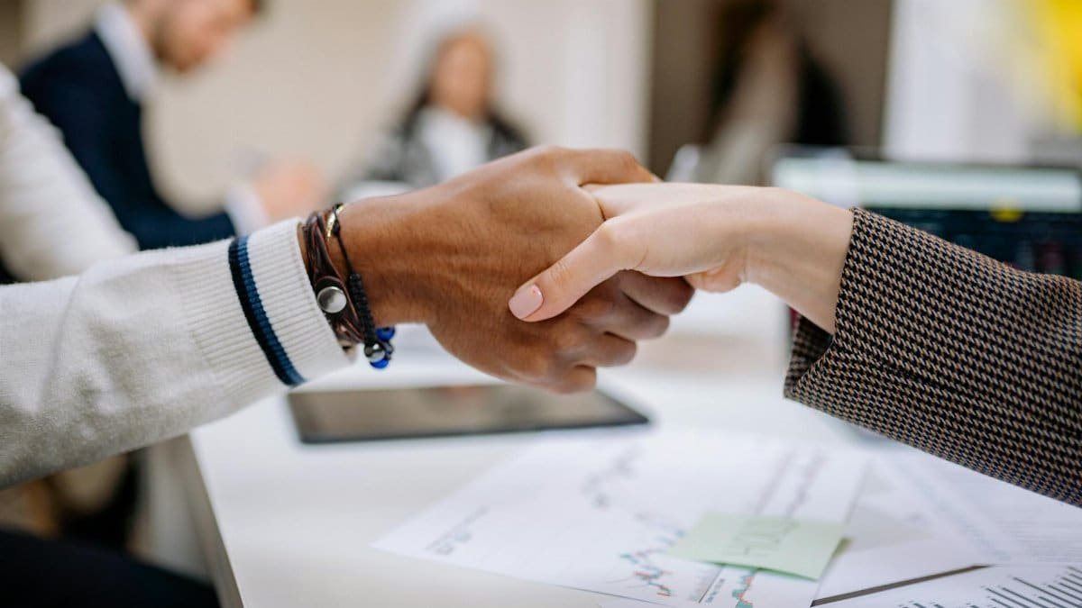 Diverse business professionals exchanging handshake in an office environment, symbolizing agreement.