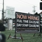 Outdoor hiring sign advertising restaurant job openings with competitive wages and benefits.