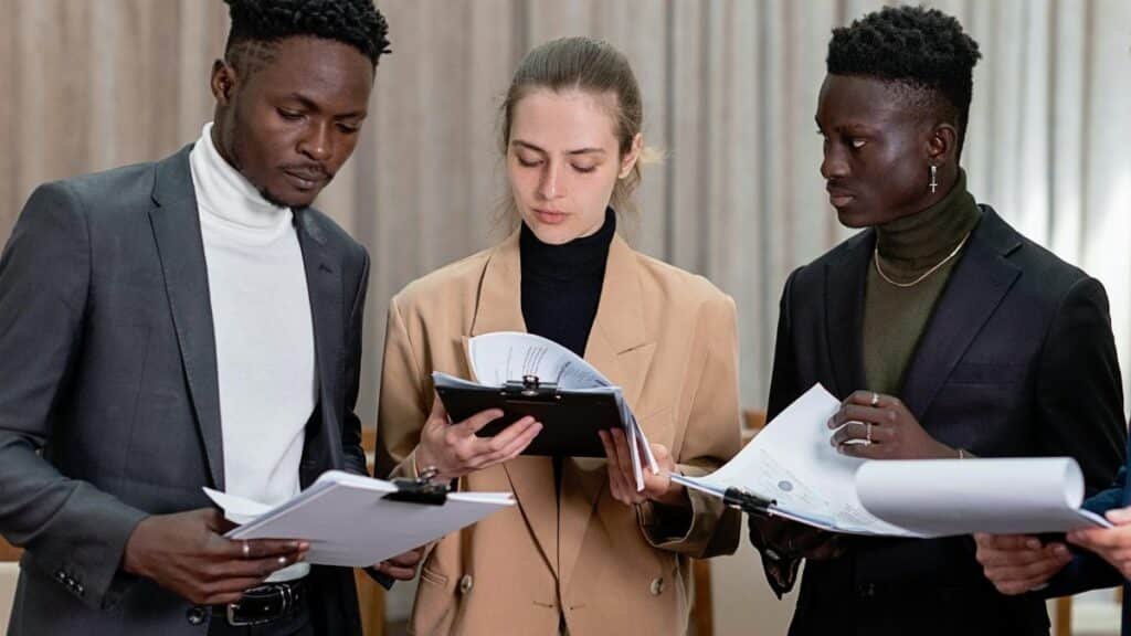 A multi-ethnic group of professionals reviewing documents together in a corporate setting.