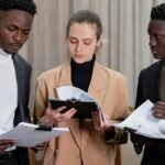 A multi-ethnic group of professionals reviewing documents together in a corporate setting.