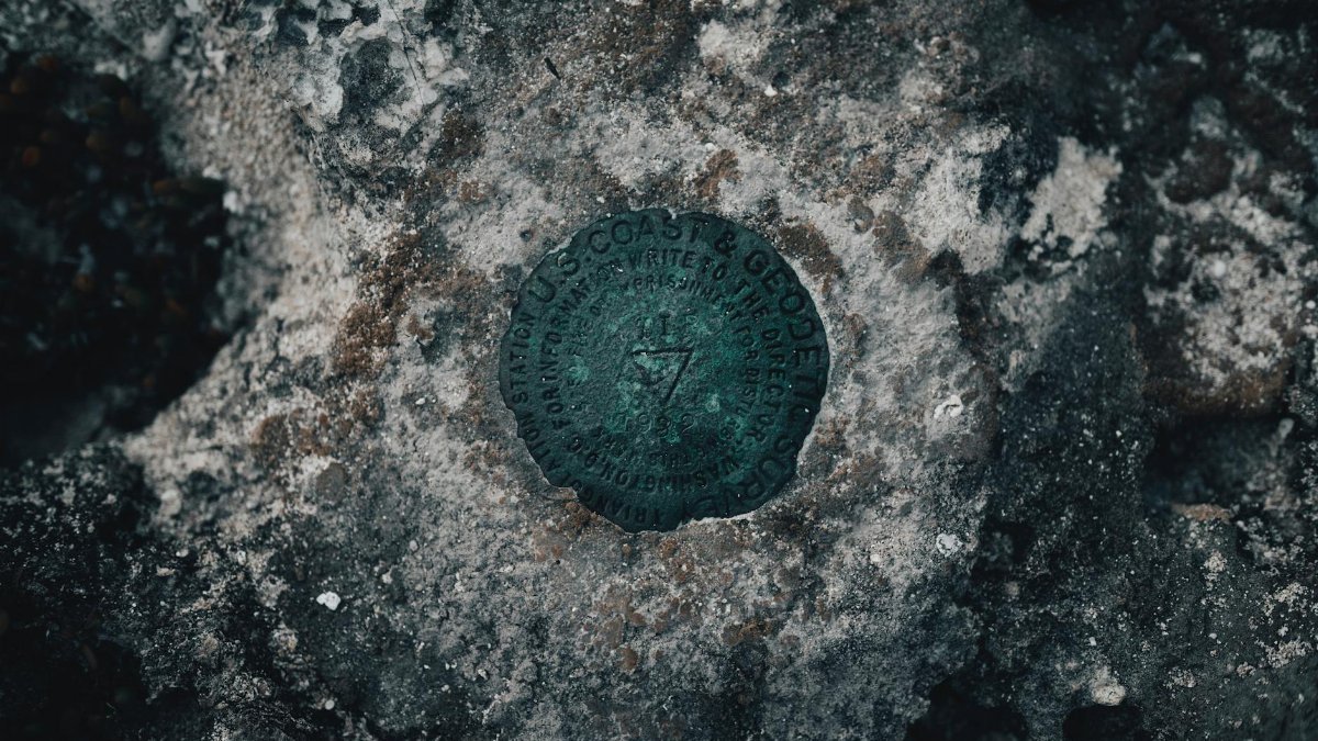 Detailed close-up of a geodetic survey mark embedded in a weathered rock surface.