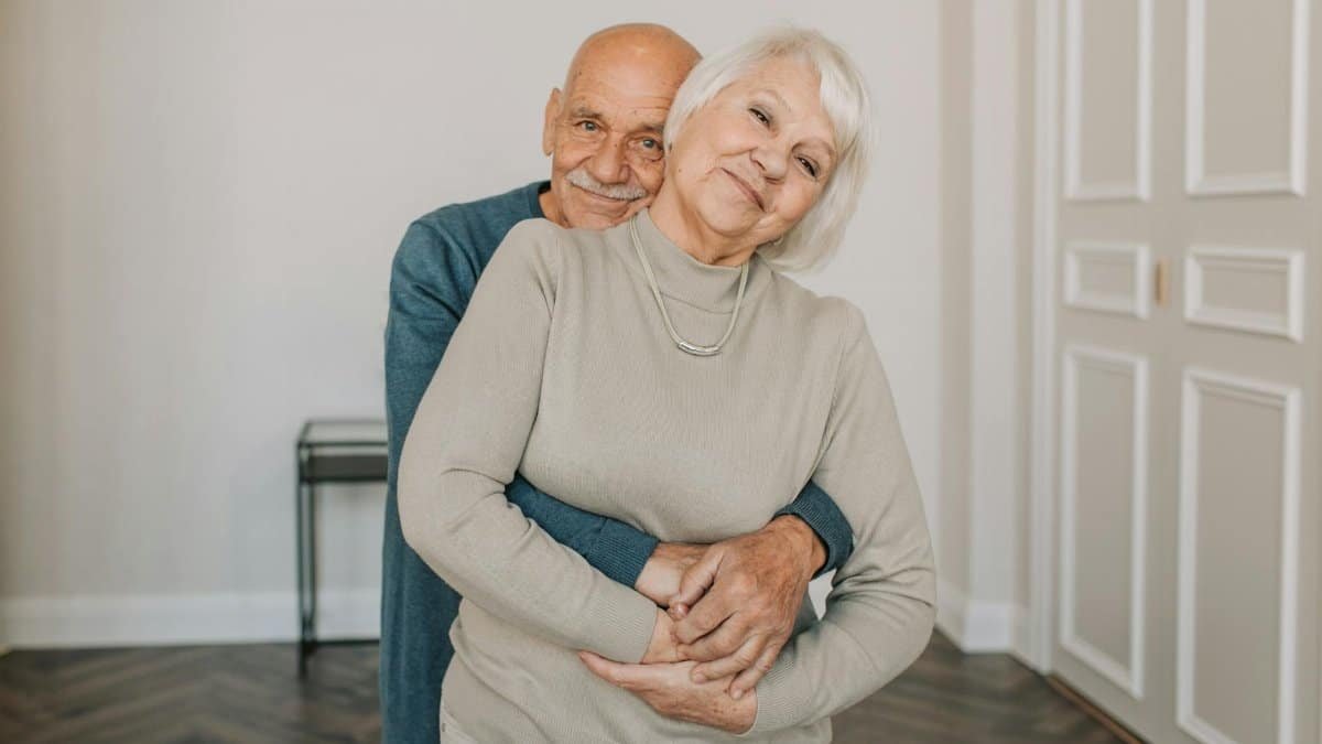 Heartwarming portrait of an elderly couple embracing happily indoors, showcasing love and companionship.