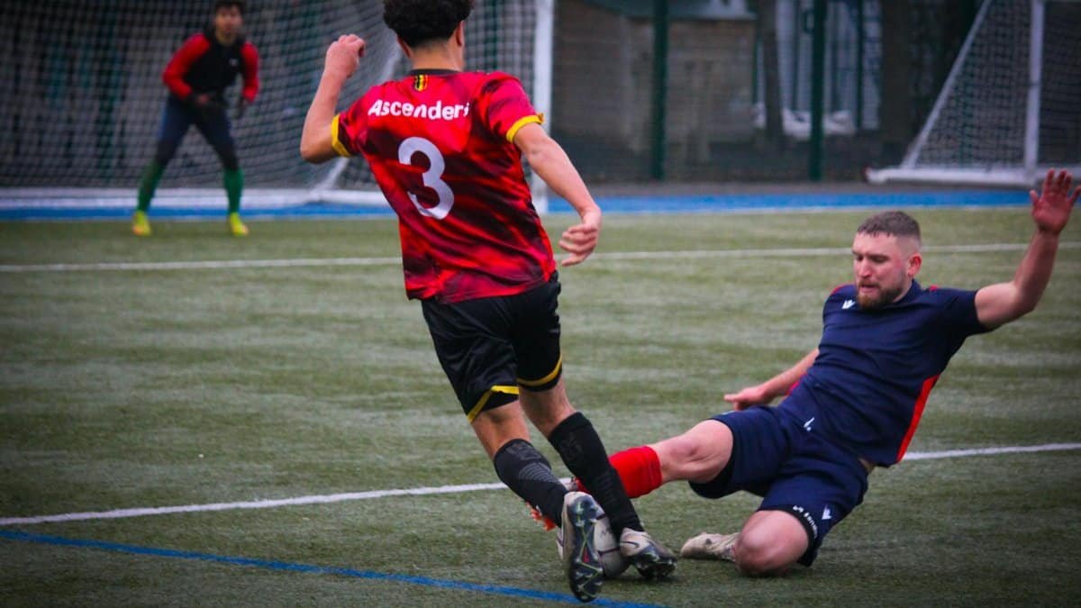 Intense soccer game with a player tackling another on a green field.