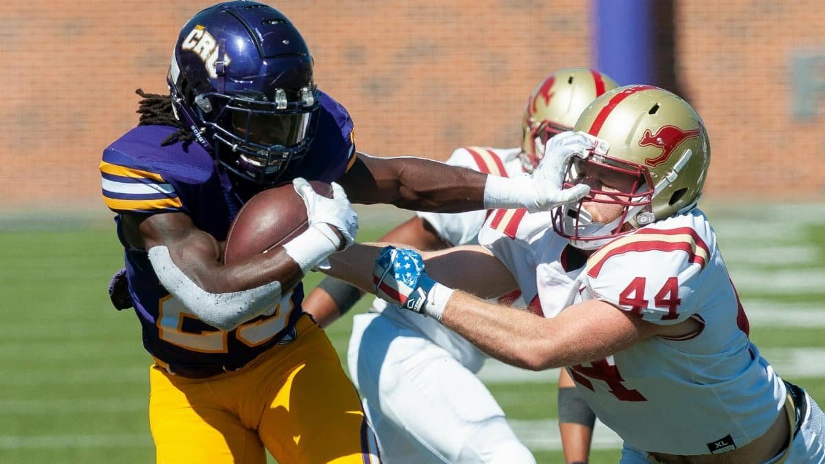 Dynamic on-field action of tackling during an American football game.