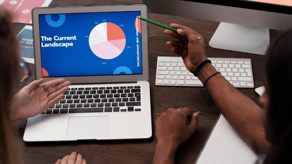 Team discussing data with graph on laptop screen in office setting.