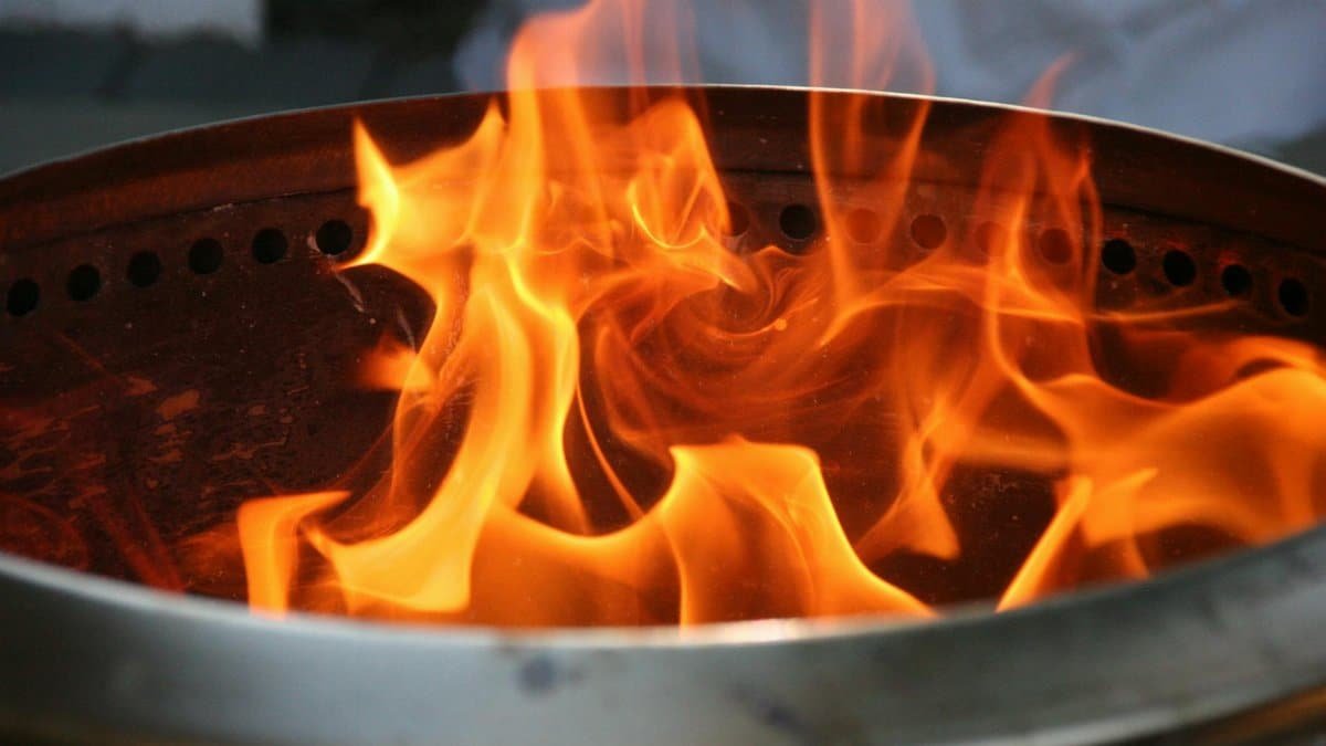 Close-up image of bright orange flames dancing inside a metal fire pit.