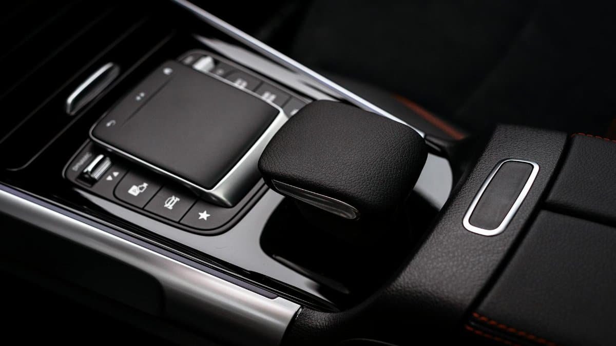 Close-up of a sleek luxury car's modern gear console, featuring leather and high-tech controls.