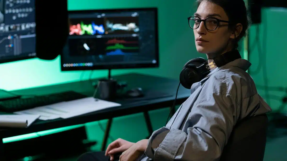 A focused young woman working with computer monitors in a modern tech environment.