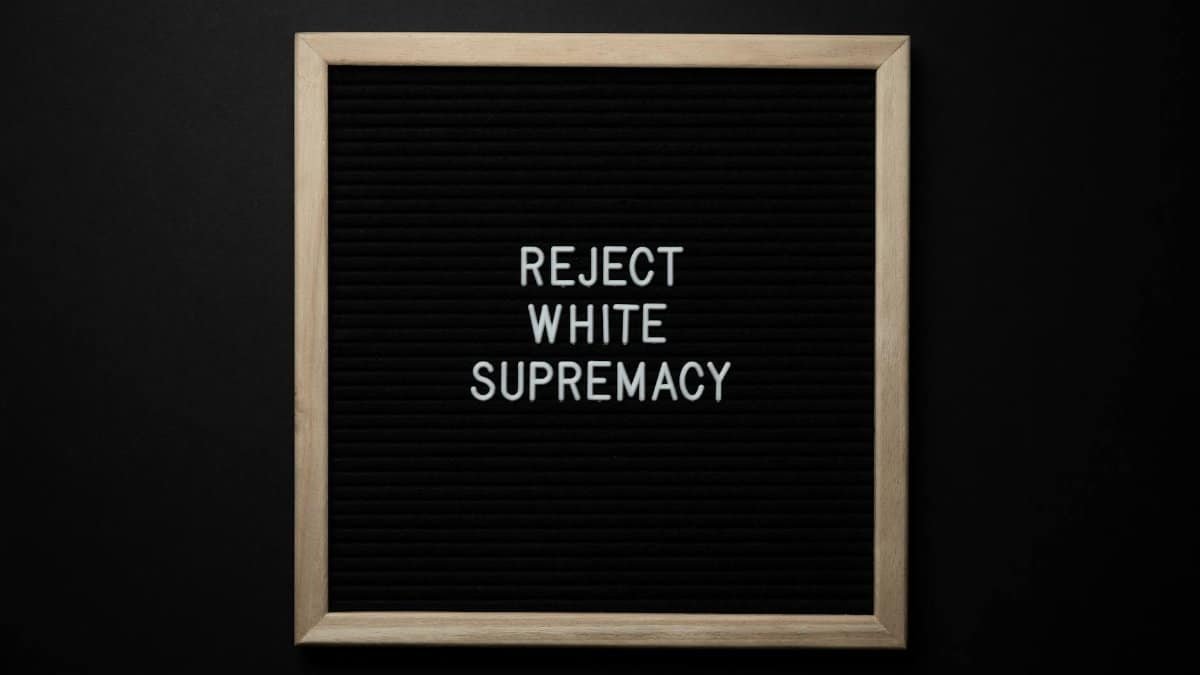 Top view of blackboard with written white REJECT WHITE SUPREMACY words on center on black background