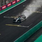 Formula 1 car speeding on wet track during race. High-energy motorsport action.