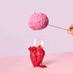 Artistic photo of a hand holding a brain-shaped candle while a heart candle burns below, symbolizing intellect vs emotion.